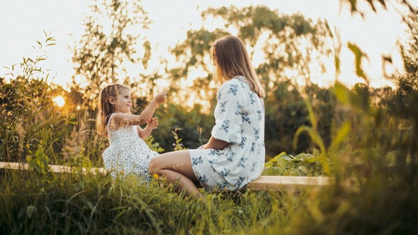 a woman and a little girl sitting on a bench